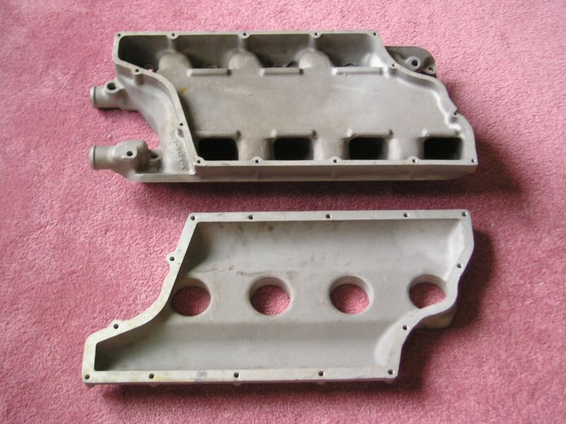 two aluminum intake manifold halves on a pink surface
