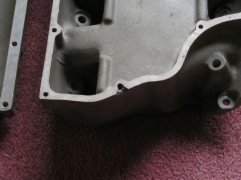 2000 Ford Mustang - This is a close-up view of a metal engine intake manifold part, showing bolt holes and a small crack.