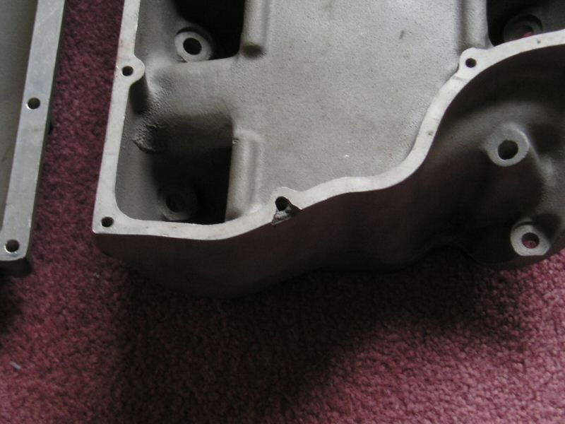 Bare cast aluminum intake manifold underside resting on maroon carpet