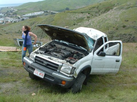 1994 Jeep YJ - White Toyota Tacoma pickup truck sustained significant damage and is parked on a grassy slope.
