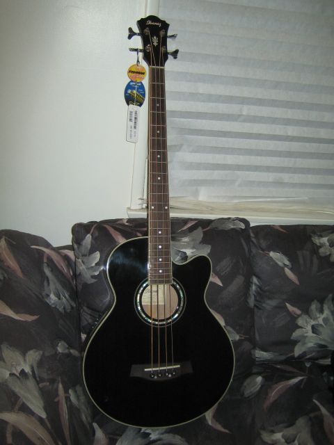 1968 Ford Mustang - An Ibanez acoustic bass guitar is shown in a full-body view, leaning against a couch.