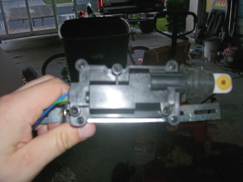 1991 Ford Bronco - A hand holds a black door lock actuator with visible wires against a blurred background.