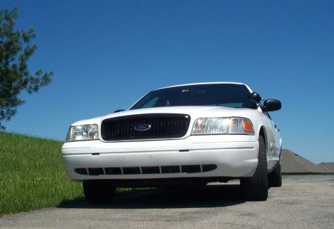 2001 Ford Crown Victoria - A white 2001 Ford Crown Victoria is parked outdoors under a clear blue sky.