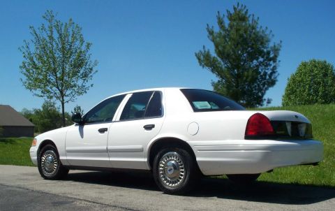 2001 Ford Crown Victoria - Rear quarter view of a white 2001 Ford Crown Victoria sedan under a clear blue sky.