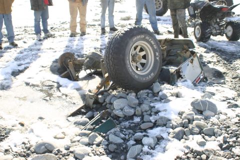 2003 Jeep TJ - A wrecked vehicle chassis lies on a rocky, snowy ground with a tire obscuring the view.