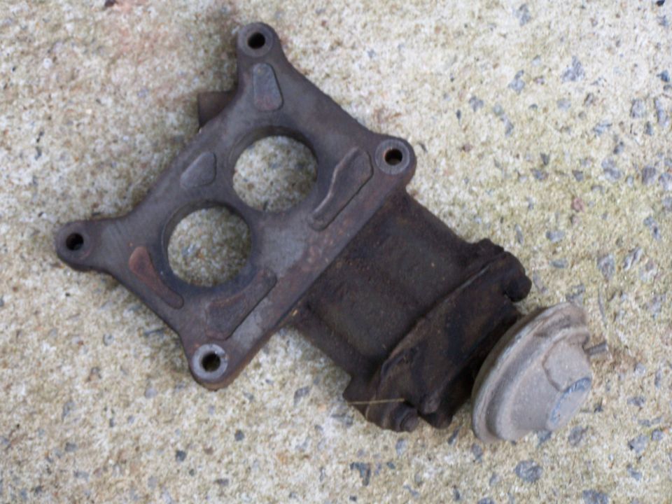 old exhaust manifold part with two circular openings and a vacuum actuator