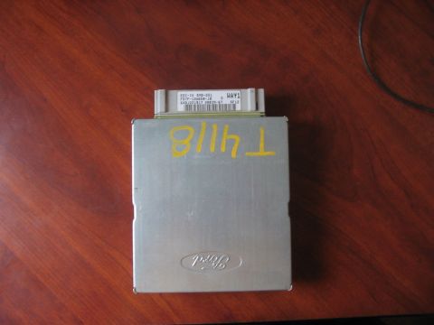 1991 Ford Bronco - A silver Ford engine control unit with yellow markings and a Ford logo is shown on a wooden surface.
