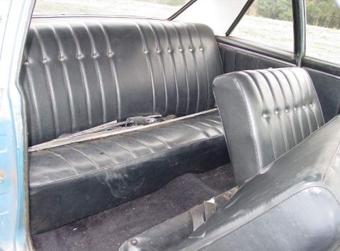 1964 Pontiac Tempest - The interior of a car shows the rear bench seat and a portion of the front seat, with carpeting on the floor.