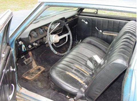 1964 Pontiac Tempest - Interior view of a 1964 Pontiac Tempest, showing worn black seats and a dashboard with gauges.