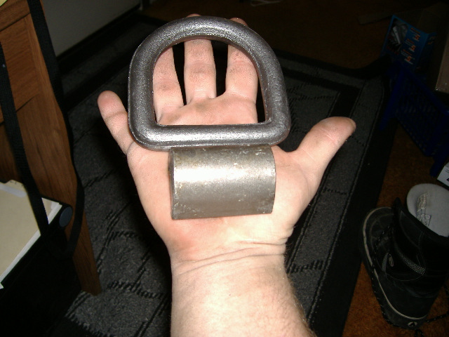 Metal D-ring and a short metal cylinder held in a person's palm