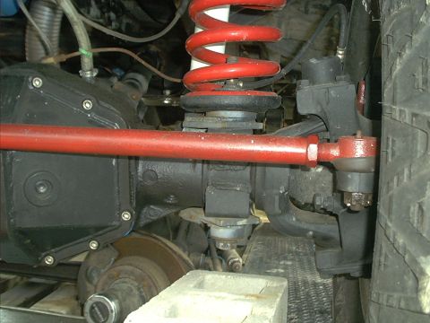 1978 Ford Bronco - Close-up view of the front axle and suspension system, showing red-painted components and part of the tire.
