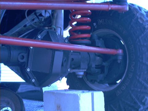 1978 Ford Bronco - Close-up view of a vehicle's suspension and differential components, including a red coil spring and a Mickey Thompson tire.