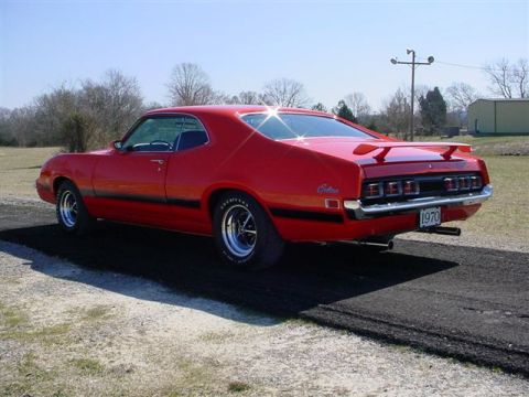 1972 Ford Ranchero - This red coupe utility vehicle features a spoiler and a black stripe along its side, with a 1970 license plate visible.