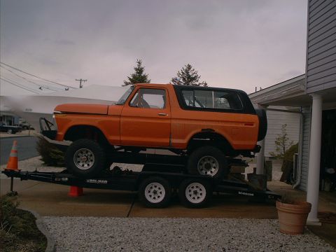 2005 Ford Excursion - This orange Ford Bronco is loaded onto a trailer for transport.