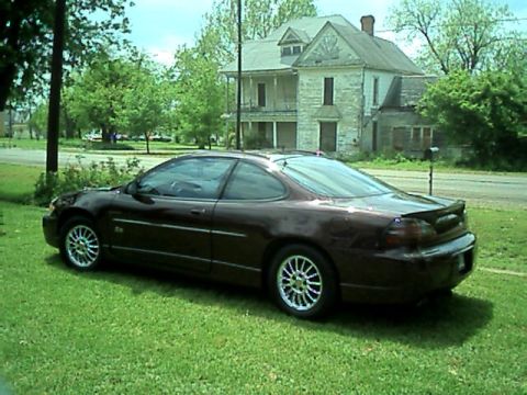 2002 Pontiac Grand Prix - A two-door Pontiac Grand Prix is parked on a grassy lawn with an old house in the background.