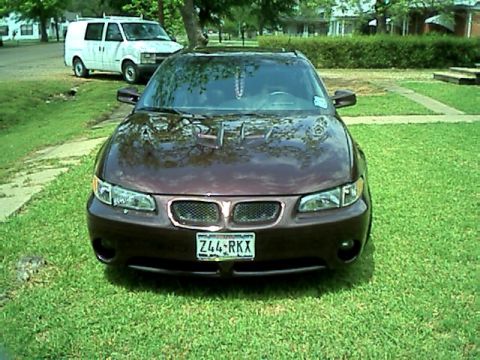 2002 Pontiac Grand Prix - A maroon 2002 Pontiac Grand Prix is parked on a grassy lawn, with a white van visible in the background.