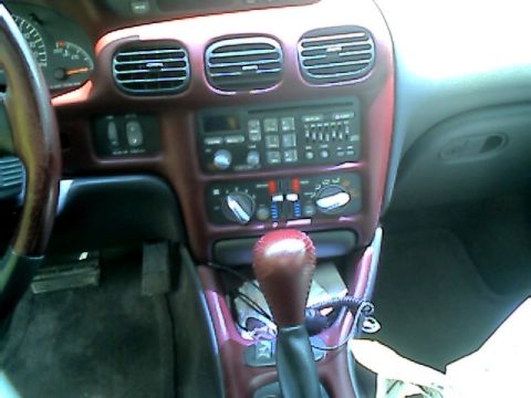 2002 Pontiac Grand Prix - The interior of a 2002 Pontiac Grand Prix features a wood-grain accented dashboard with a prominent gear shifter.