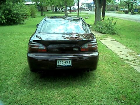 2002 Pontiac Grand Prix - The rear of a dark red 2002 Pontiac Grand Prix is shown parked on grass, its distinctive taillights and dual exhaust pipes.