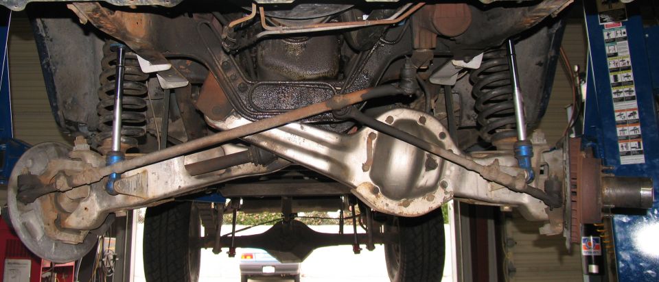 Undercarriage view of a vehicle's rear axle, suspension, and brake components