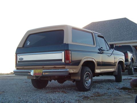 1986 Ford Bronco - Rear view of a two-tone 1986 Ford Bronco parked on gravel.