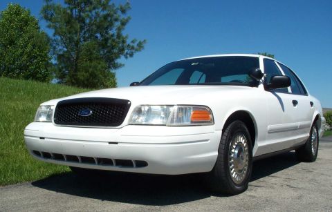 2001 Ford Crown Victoria - A white 2001 Ford Crown Victoria is shown from a three-quarter front angle under a clear blue sky.