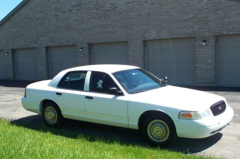 2001 Ford Crown Victoria - White 2001 Ford Crown Victoria sedan parked outdoors in front of a building with multiple garage doors.