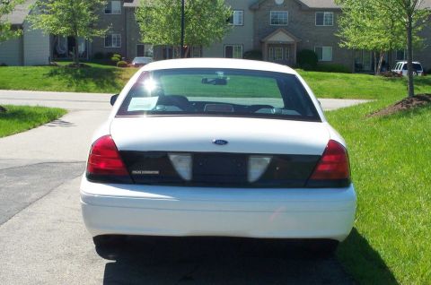 2001 Ford Crown Victoria - The rear of a white Ford Crown Victoria Police Interceptor is parked on a driveway.