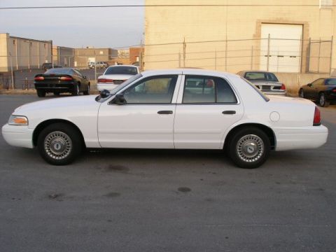 2001 Ford Crown Victoria - Side profile of a white 2001 Ford Crown Victoria sedan in a parking lot with other vehicles.