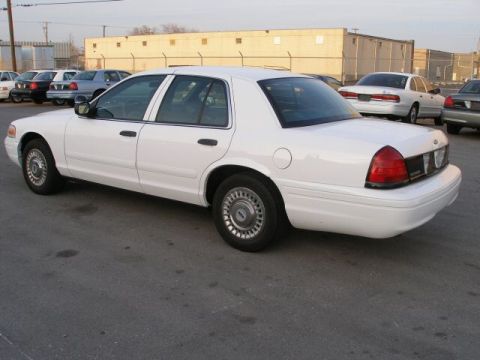 2001 Ford Crown Victoria - A white 2001 Ford Crown Victoria is shown from the side in a parking lot with other vehicles visible.