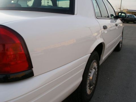 2001 Ford Crown Victoria - A white sedan is shown from the rear passenger side, with a dark sedan in the background.