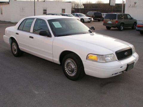 2001 Ford Crown Victoria - A white 2001 Ford Crown Victoria is parked in a lot with other vehicles visible in the background.