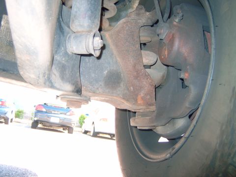1993 Ford Explorer - A close-up shot of the vehicle's suspension system and brake components, with other cars parked nearby.