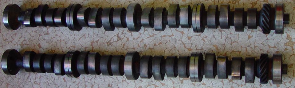 Two used V8 camshafts side by side showing lobes, journals and helical distributor gears