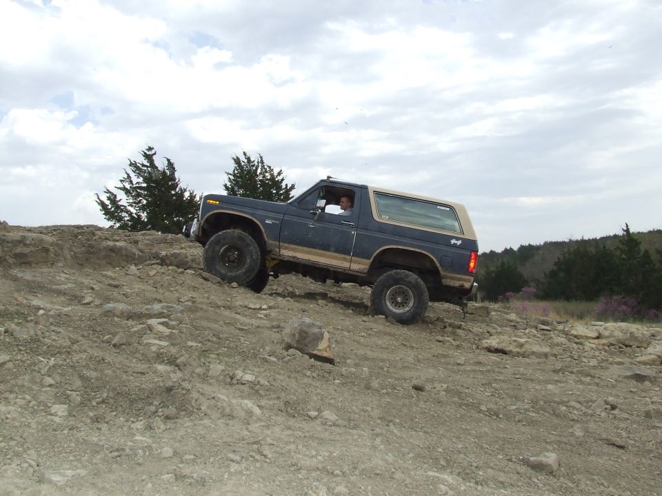 Blue 1986 Ford Bronco climbing a rocky incline