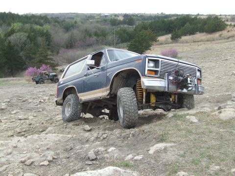 1986 Ford Bronco - This lifted Ford Bronco navigates a challenging off-road course with another Bronco in the distance.