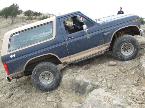 1986 Ford Bronco - This Ford Bronco is navigating a rocky terrain, demonstrating its off-road capabilities.