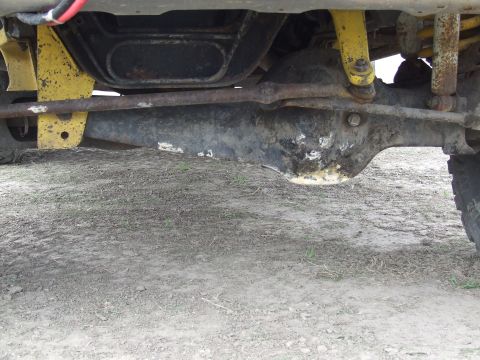 1986 Ford Bronco - Close-up view of the vehicle's undercarriage, focusing on the front axle and suspension parts.