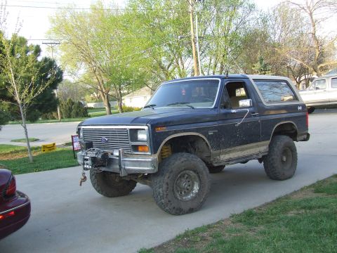 1986 Ford Bronco - Lifted Ford Bronco with aftermarket winch, parked on a driveway.