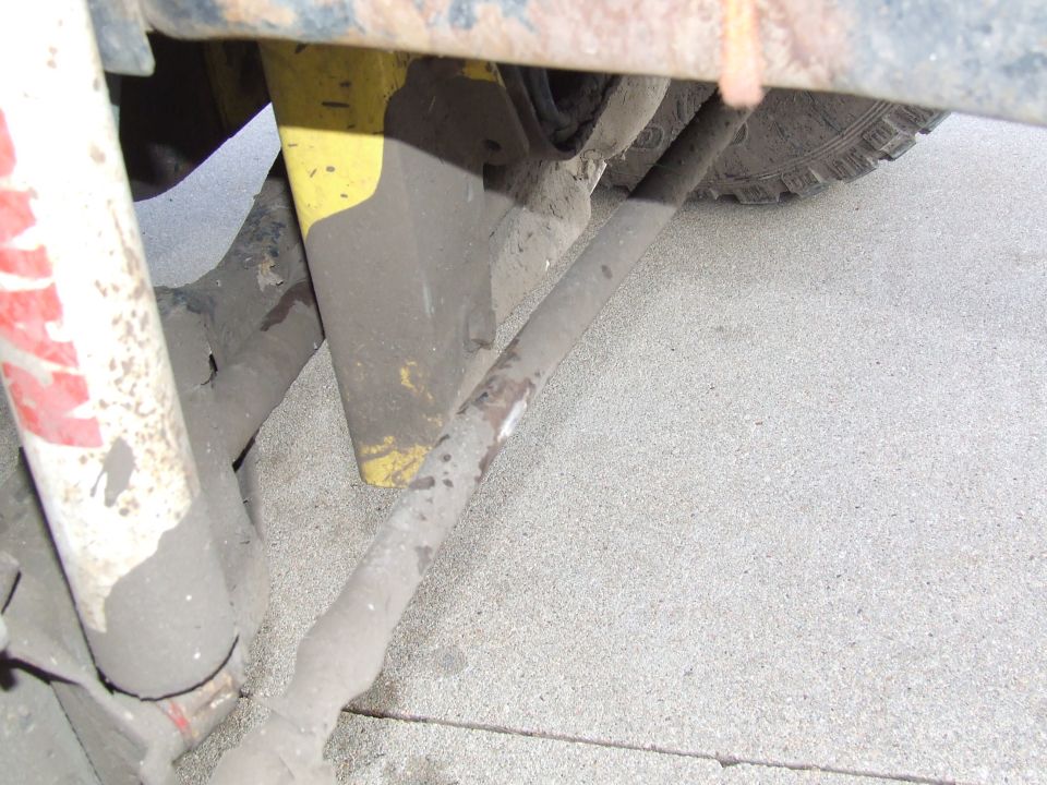 close-up of dirty suspension parts, including a shock absorber and tie rod