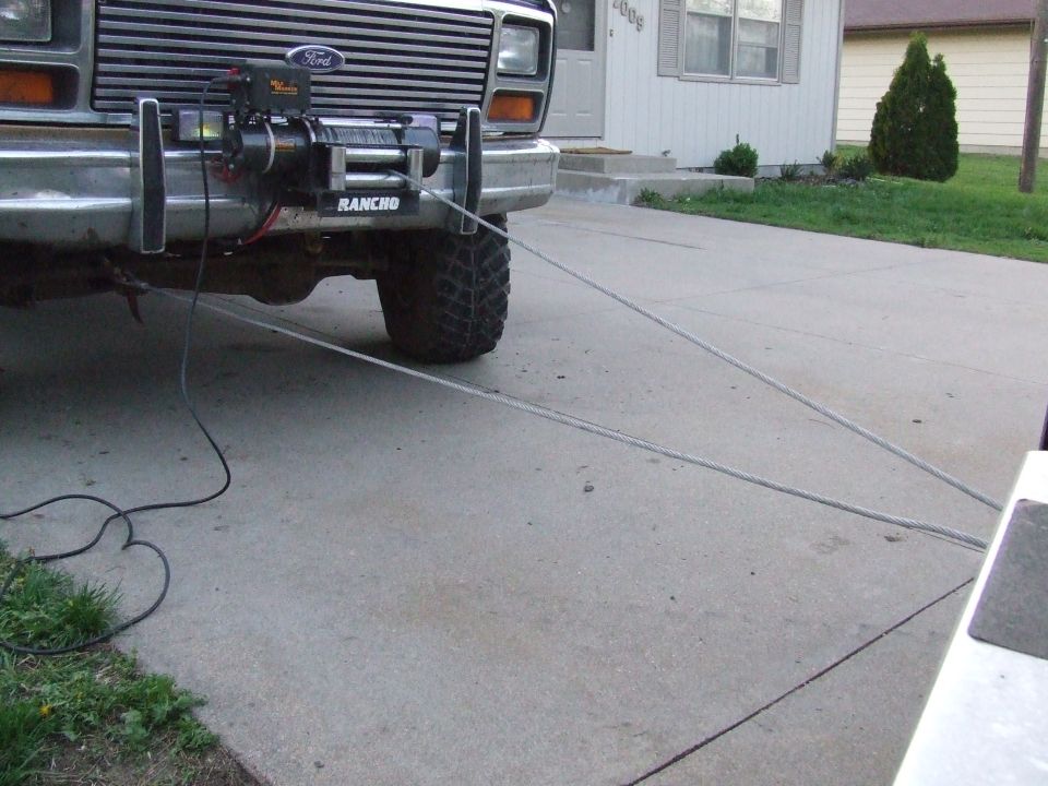 Ford truck front end with winch and tow cable attached, showing a chrome bumper and grille