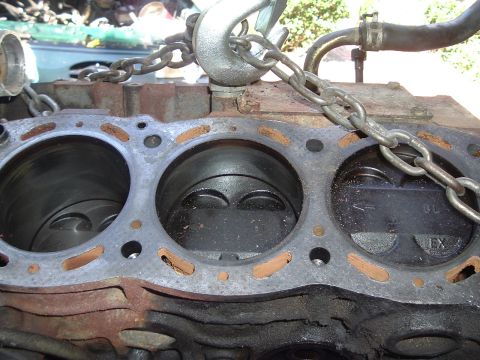 1993 Ford Taurus - Close-up of an engine block's cylinders and pistons, suspended by chains for removal or repair.