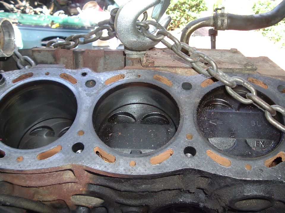 Engine block with pistons visible, held by chains