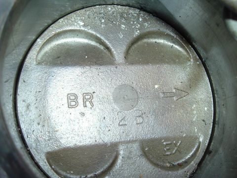 1993 Ford Taurus - Close-up of a piston top with various markings including 'BR', '2B', 'EX', and an arrow indicating direction.