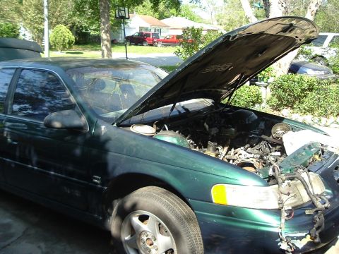 1993 Ford Taurus - Green sedan with hood open, revealing the engine compartment. The front passenger side is visible.