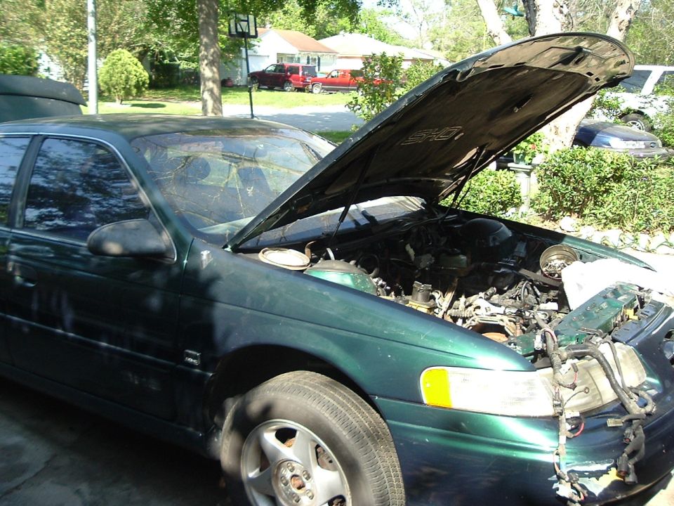 Green sedan, hood open, showing engine. Front passenger side visible