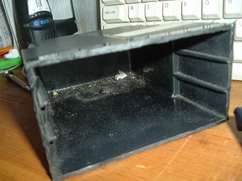 1993 Ford Taurus - This is a close-up view of a dusty and debris-filled car interior part, possibly a storage bin or console piece.