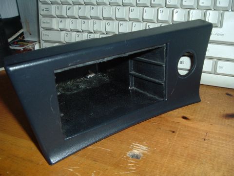 1993 Ford Taurus - This dark gray trim piece features storage cubbies and a circular cutout, likely for a gauge or button.