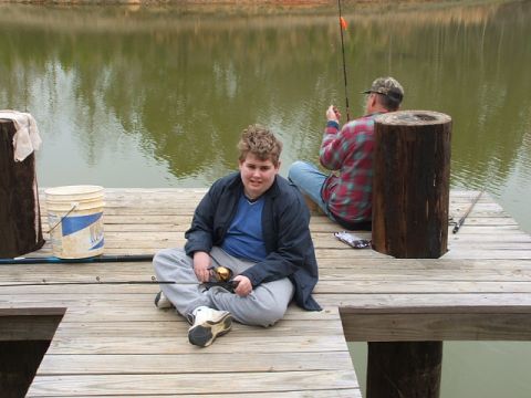 1966 Ford Ranchero - Two people enjoy a day of fishing on a wooden dock next to a calm body of water.