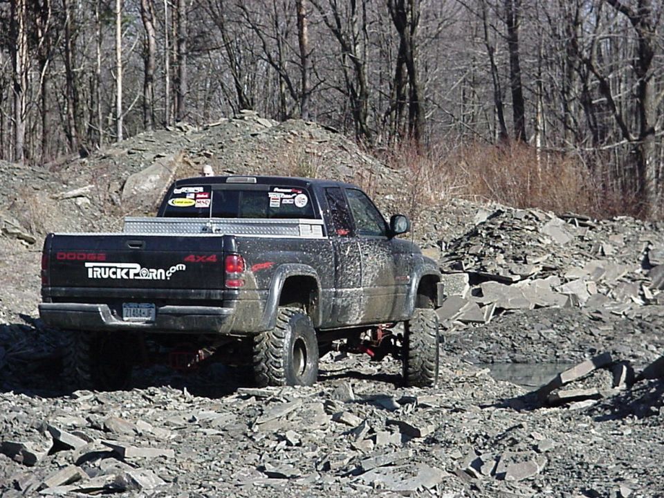 1998 Dodge 1500 pickup truck with "TRUCKPORN.com" decal on tailgate, driving on rocky terrain