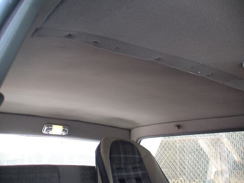 1993 Ford C-350 (Centurion Conversions) - The headliner of a vehicle shows some wear and tear, with a plaid seat visible in the foreground.